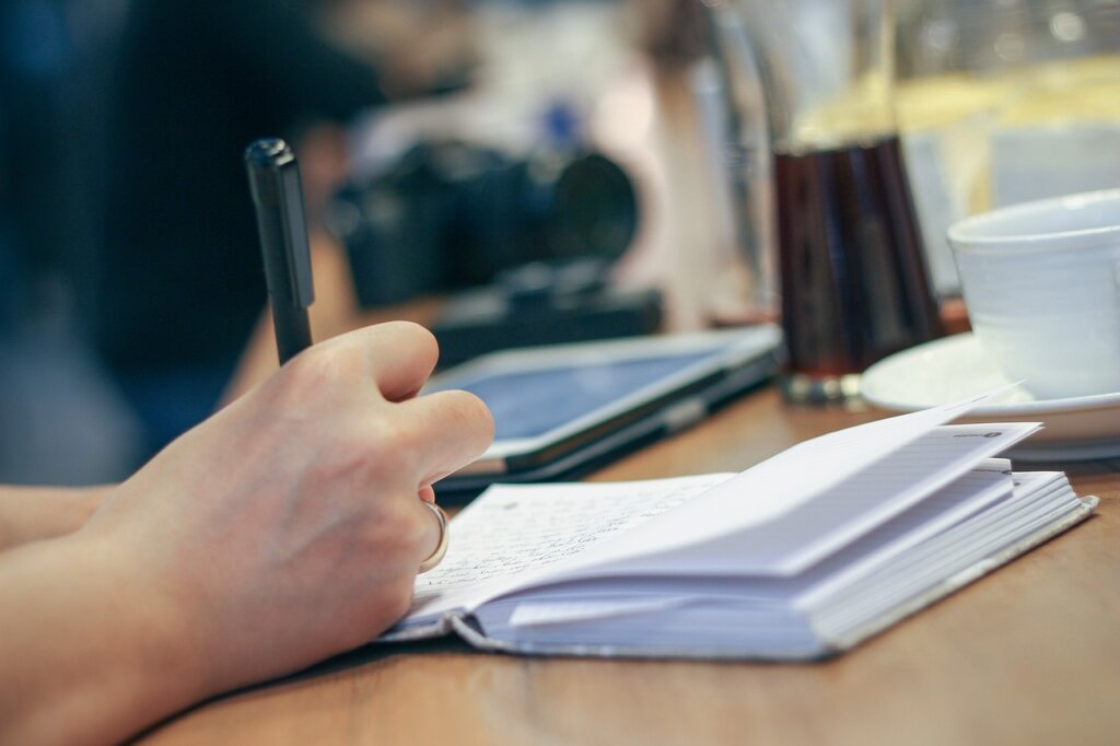 person writing important dates in a notebook with pen