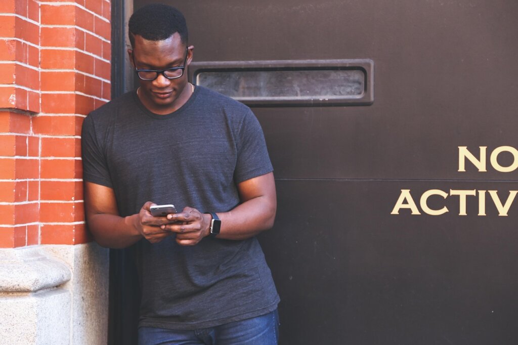 young person checking savings account on smartphone at cafe