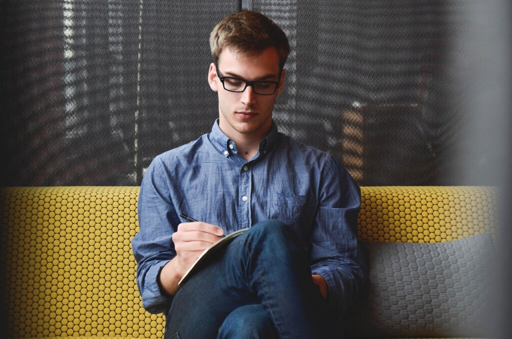 man writing business plan on notebook late at night with coffee
