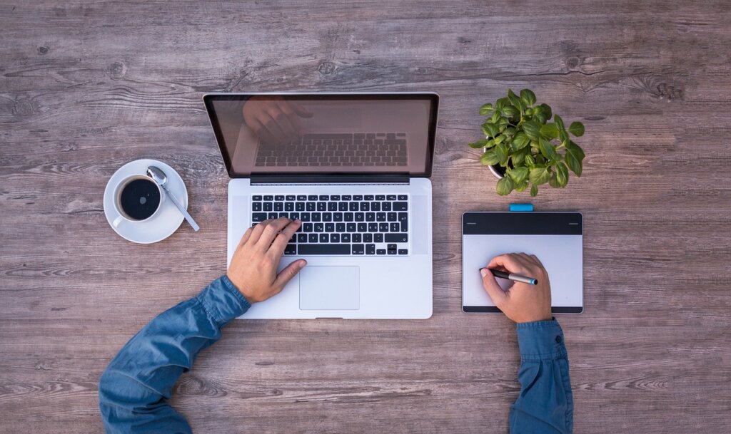 freelance designer working on tablet with financial documents on table