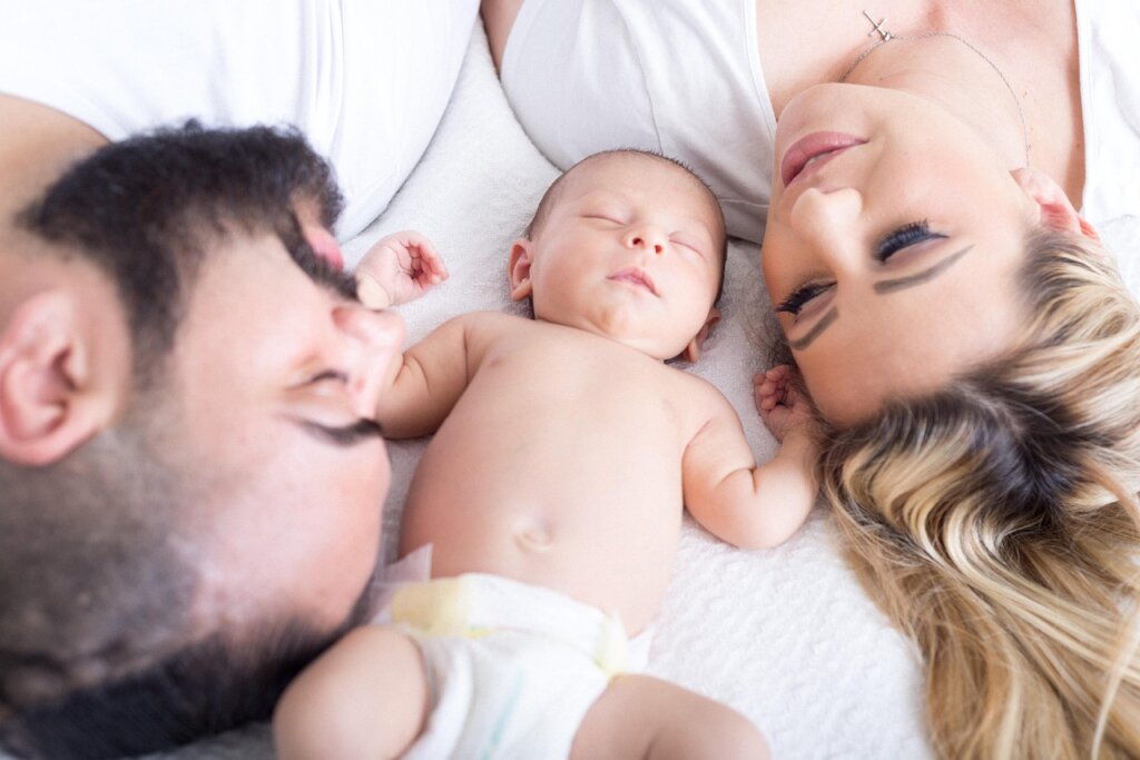 newborn baby receiving medical check at hospital with national happiness card beside