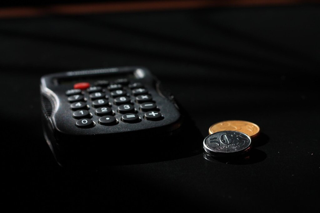 calculator and coins on a white table representing wage deduction