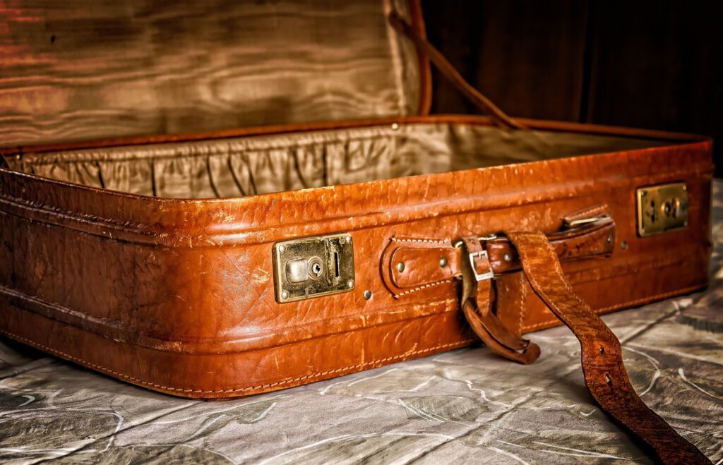 empty open suitcase on bed before packing