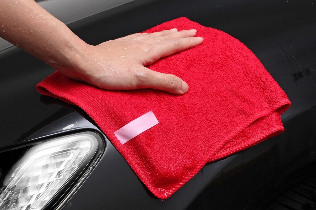 microfiber cloth wiping bathroom mirror after shampoo application