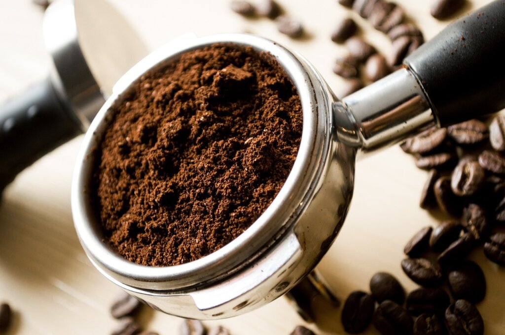 dried coffee grounds stored in glass airtight container on kitchen shelf