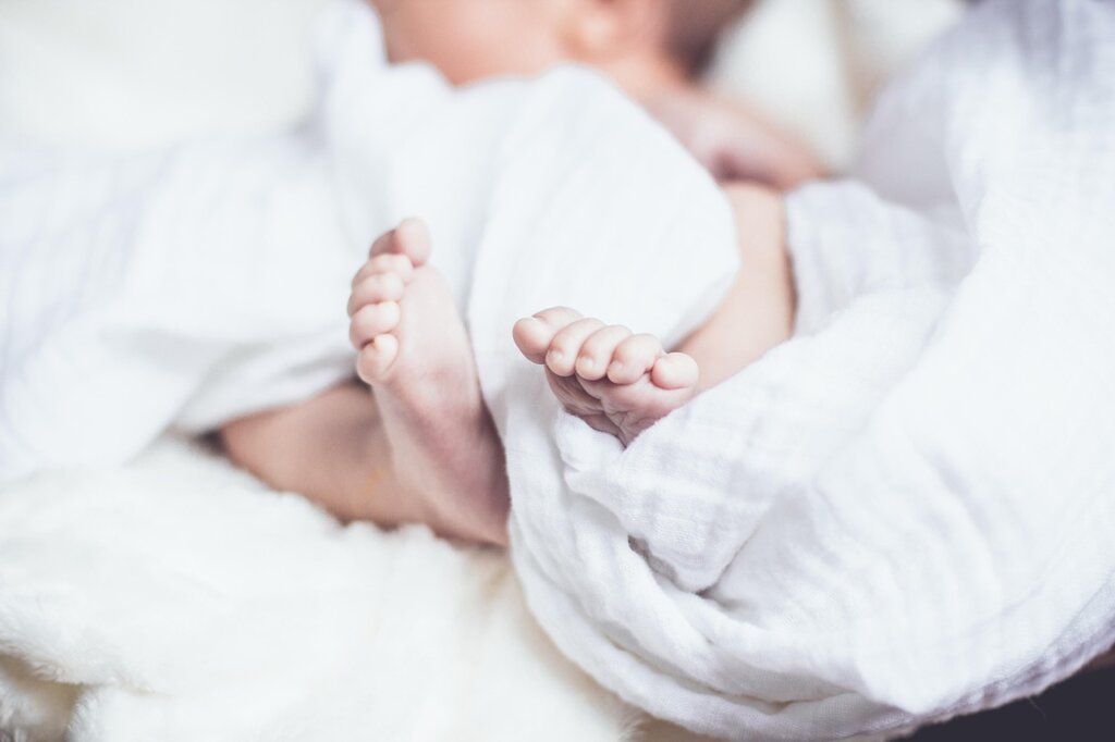parent covering baby with light blanket in air-conditioned room