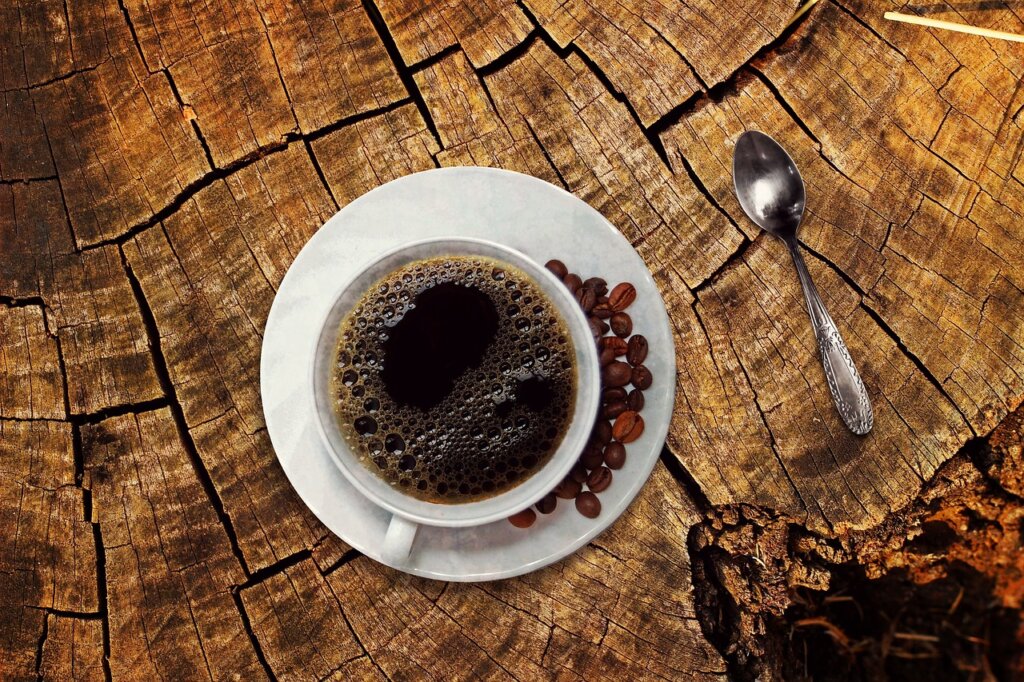 linen pouch with activated charcoal and dried coffee grounds on wooden table